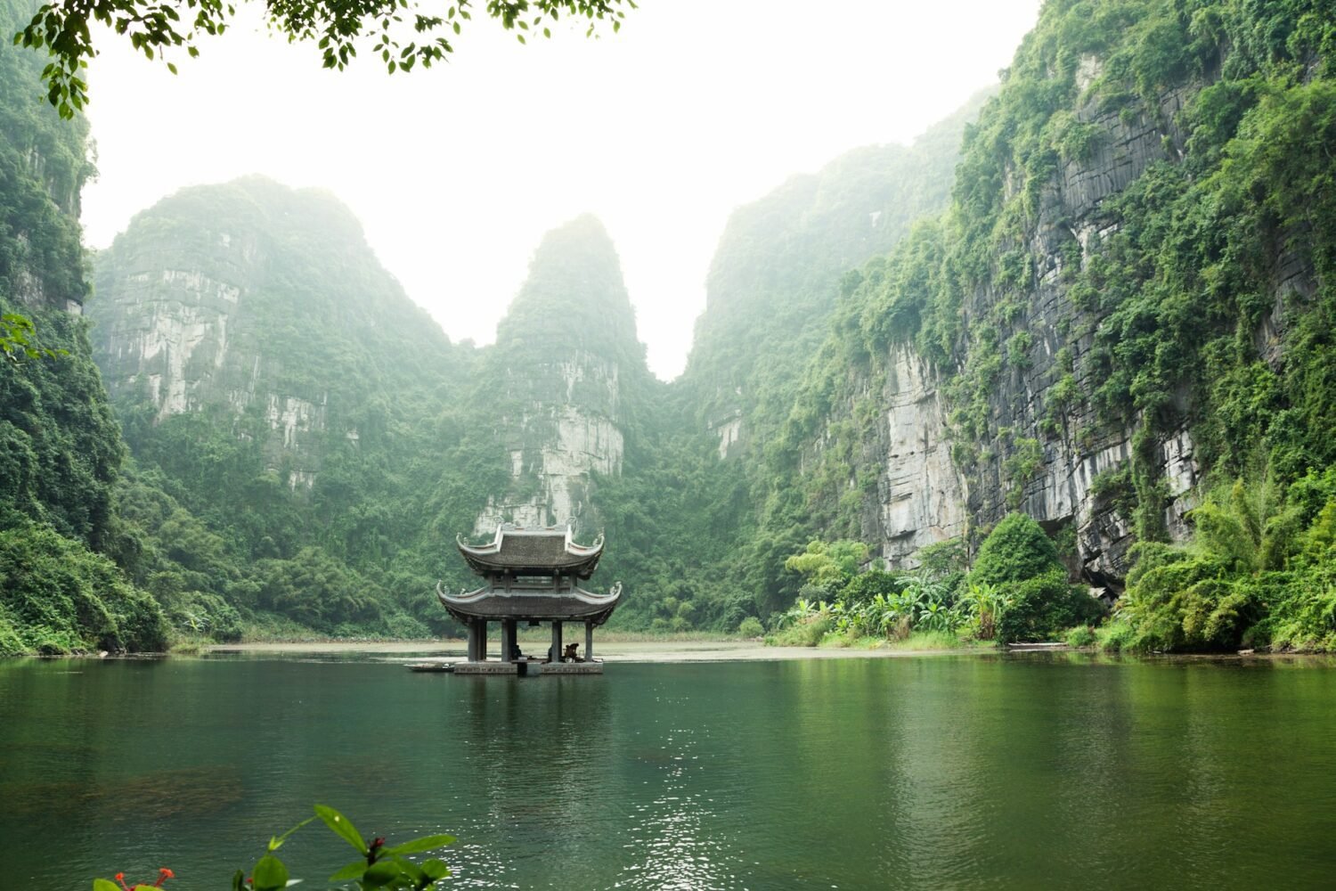 Picture of a small hut in the middle of the lake surrounded by mountains in Ninh Binh