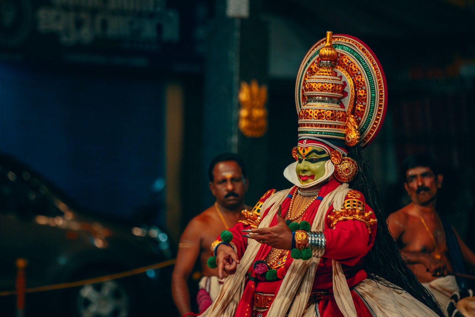 kathakali dancer A vibrant close-up of a Kathakali dancer in traditional elaborate costume and green facial makeup, performing with expressive hand gestures during a cultural ceremony.